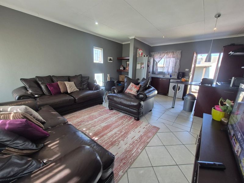 Open-plan living area featuring tiled flooring, recessed lighting, and a functional kitchen space with a breakfast bar.