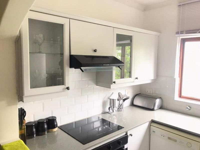 A well-maintained kitchen featuring white cabinetry, subway tile backsplash, stone countertops, and integrated appliances including an electric hob and oven.