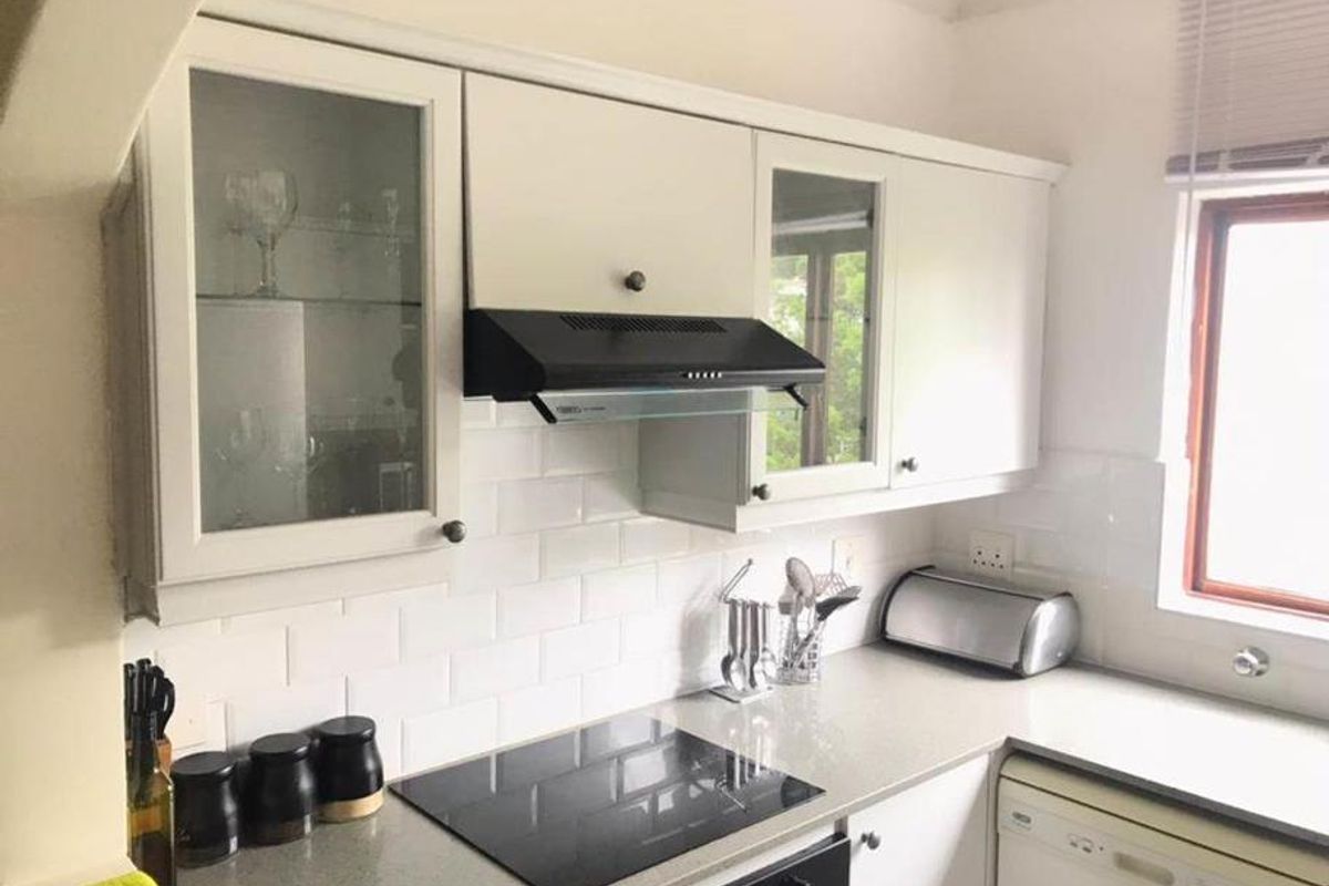 A well-maintained kitchen featuring white cabinetry, subway tile backsplash, stone countertops, and integrated appliances including an electric hob and oven.