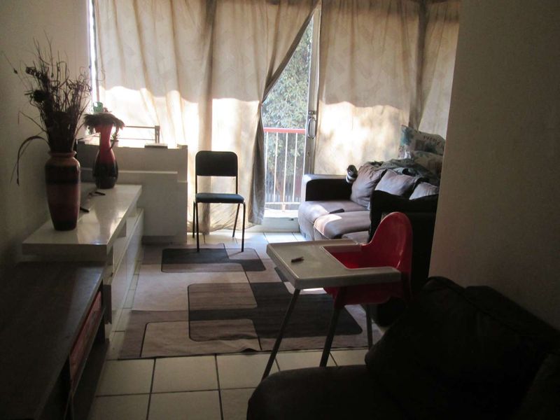 A living room area featuring tiled flooring and a sliding glass door providing access to an outdoor balcony space.