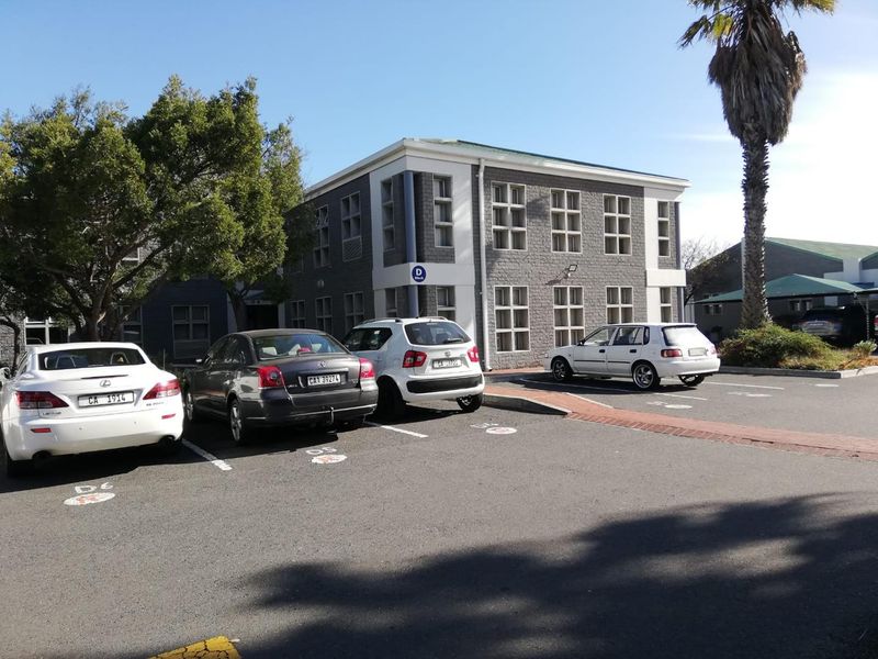 Exterior view of a multi-story office building featuring a brick facade and dedicated paved parking area.