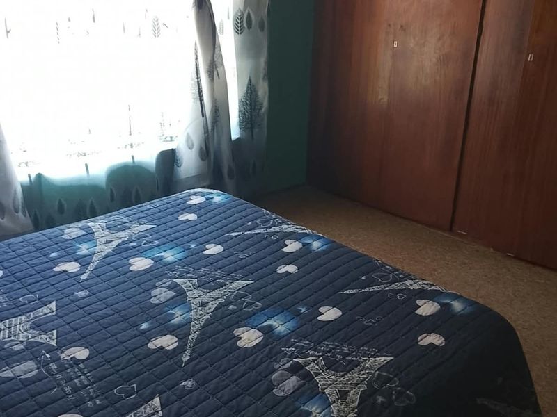 A bedroom featuring built-in wooden wardrobes and carpet flooring, offering a functional space with natural light from the window.