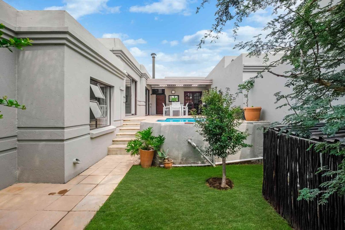 A private rear courtyard featuring a small swimming pool, paved patio area, and a compact lawn, accessible from the main living areas.