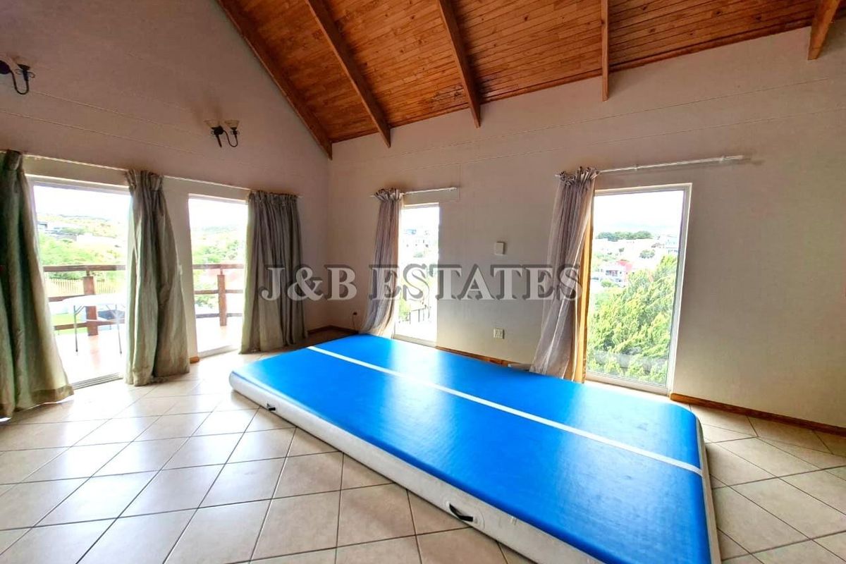 Spacious living area featuring high vaulted timber ceilings, tiled flooring, and multiple glass doors providing access to the balcony and natural light.