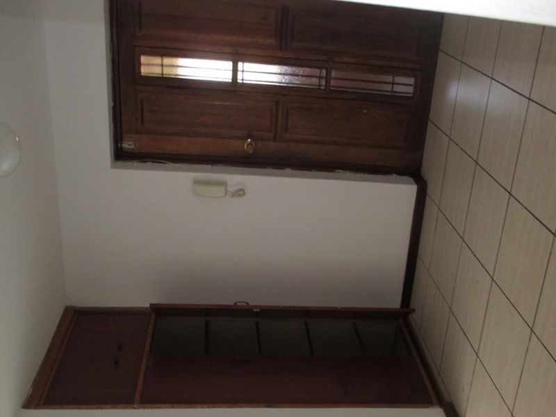 A functional hallway featuring tiled flooring, built-in wooden storage cabinetry, and a classic wooden door with glass inserts.