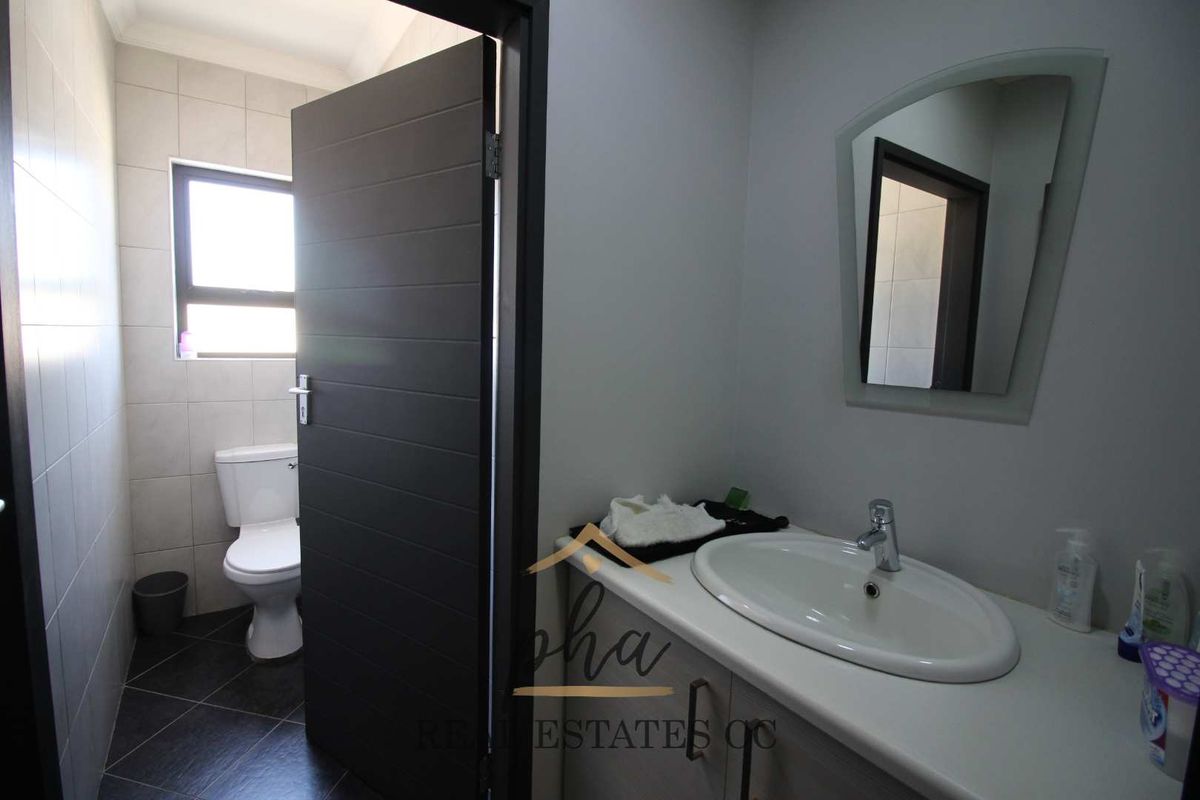 A functional bathroom featuring a vanity with a basin, a toilet, and tiled flooring, presenting a clean and well-maintained space.