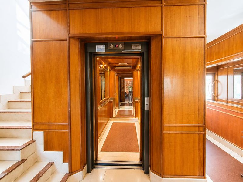 Elegant penthouse entrance featuring rich wood paneling, a private elevator, and a classic marble staircase.