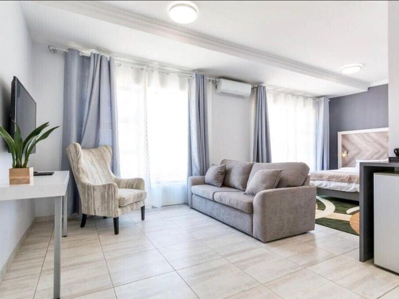 A well-maintained open-plan studio suite featuring tiled flooring, a split-system air conditioner, and integrated bedroom and living areas.