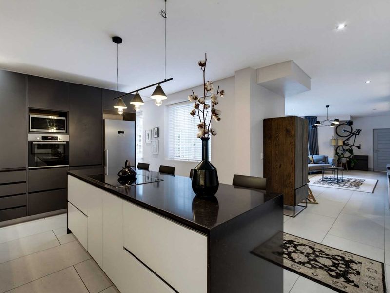 Modern open-plan kitchen and living area featuring a sleek kitchen island, built-in appliances, and contemporary tiled flooring throughout.