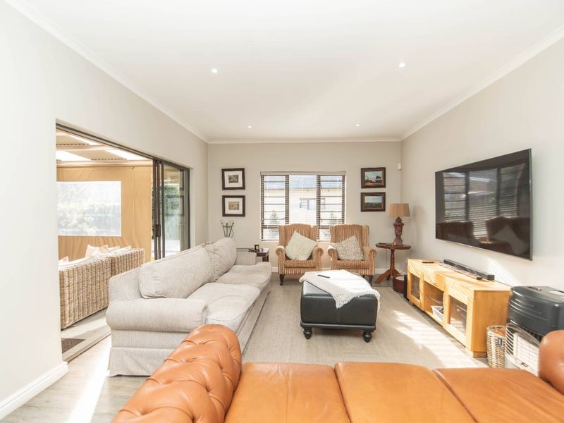 A bright and spacious living room featuring recessed downlights, coving, and large sliding glass doors that provide seamless access to the outdoor patio area.