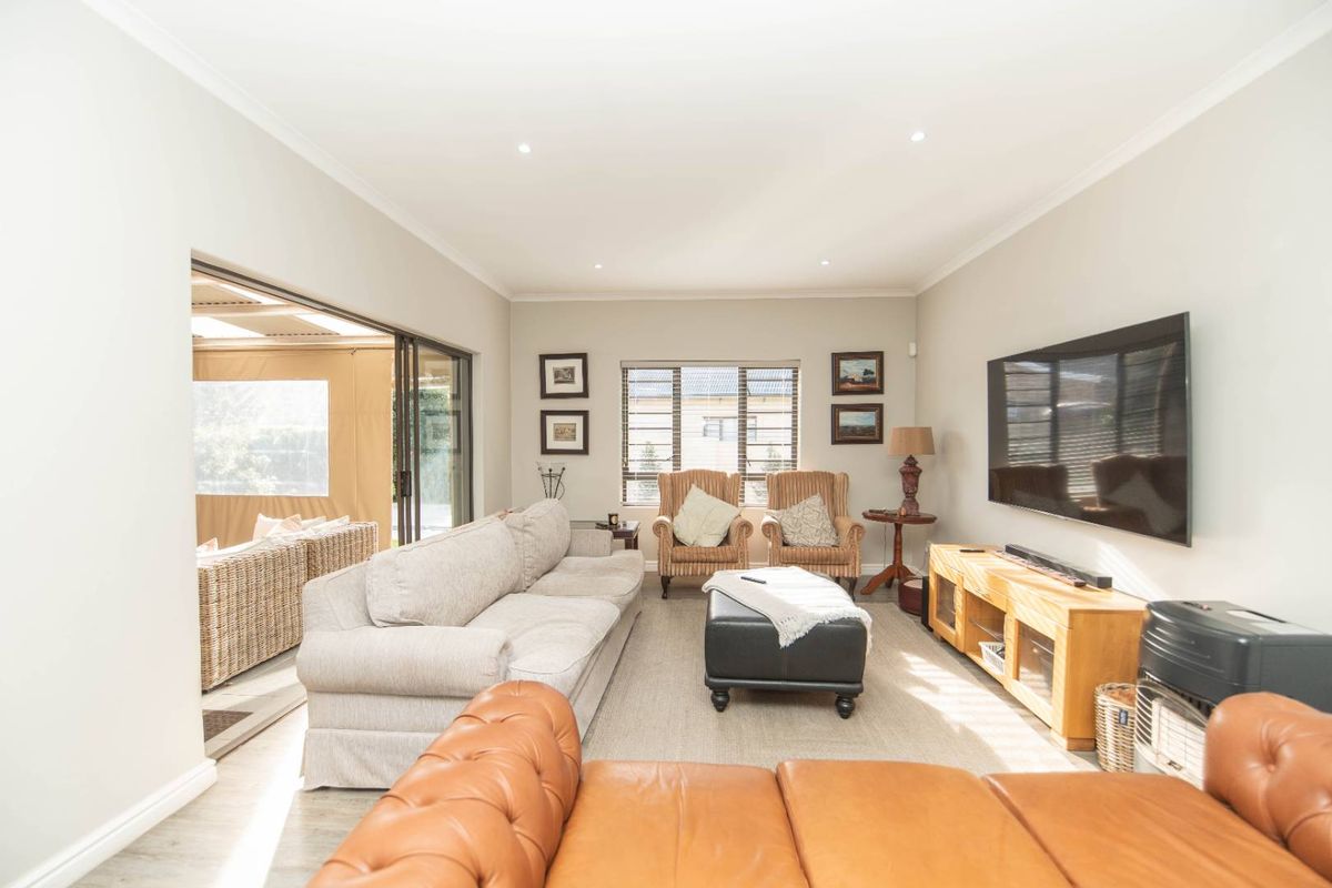 A bright and spacious living room featuring recessed downlights, coving, and large sliding glass doors that provide seamless access to the outdoor patio area.