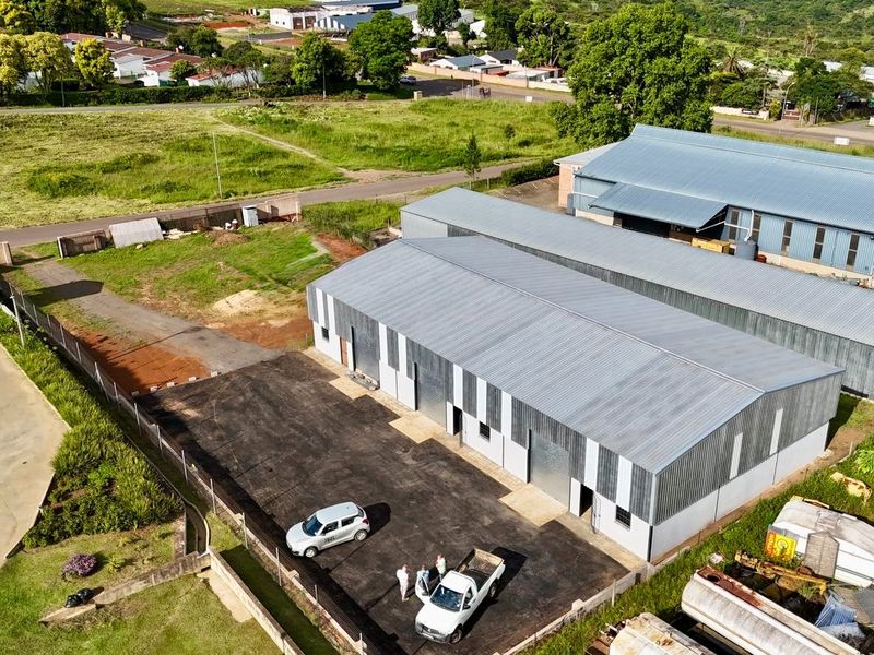 Aerial view of an industrial property featuring multiple warehouse units with corrugated metal roofing, paved yard space, and secure perimeter fencing.