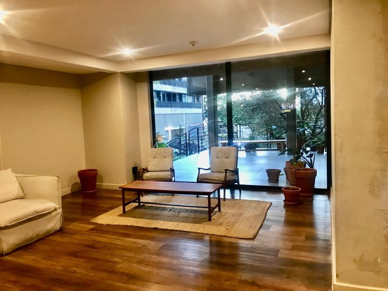 Spacious living area featuring warm timber flooring, recessed downlighting, and large sliding glass doors that open onto an outdoor patio space.