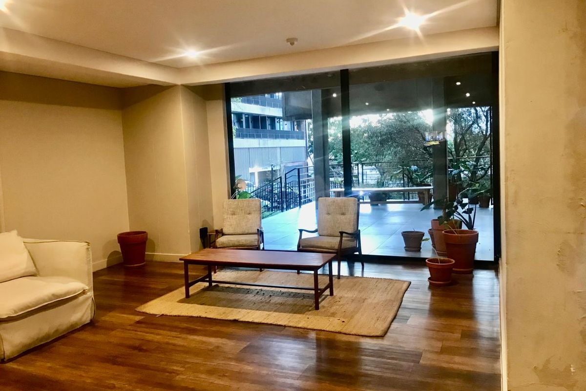 Spacious living area featuring warm timber flooring, recessed downlighting, and large sliding glass doors that open onto an outdoor patio space.