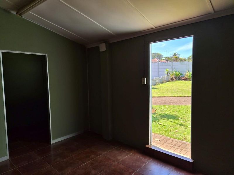 An empty interior room featuring tiled flooring and direct access to the rear garden area.
