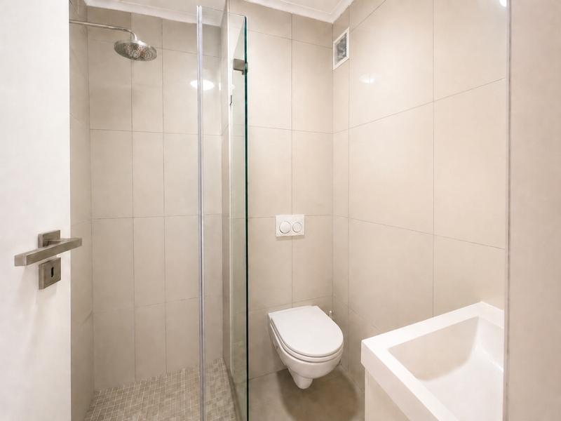 Modern bathroom featuring a walk-in shower with glass screen, wall-mounted toilet with concealed cistern, and a sleek vanity basin with neutral wall tiling.