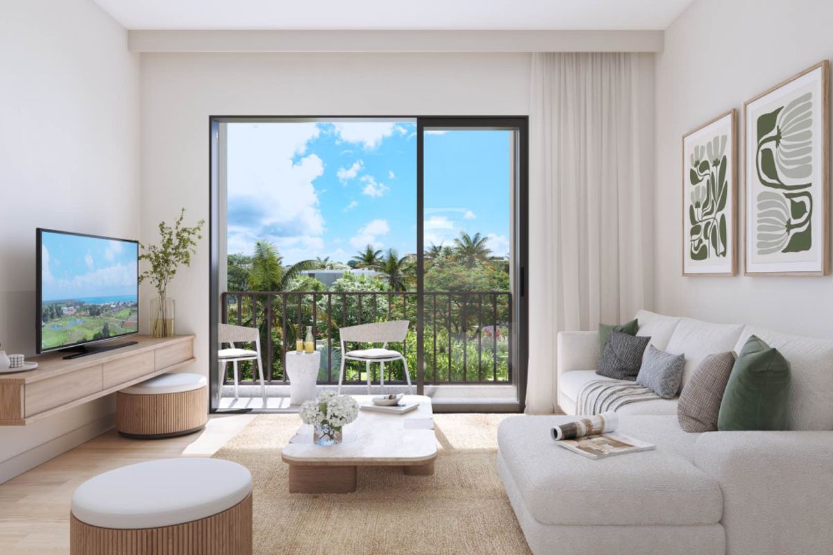 A bright and modern living room featuring a large sliding glass door that opens onto a private balcony with lush tropical views.