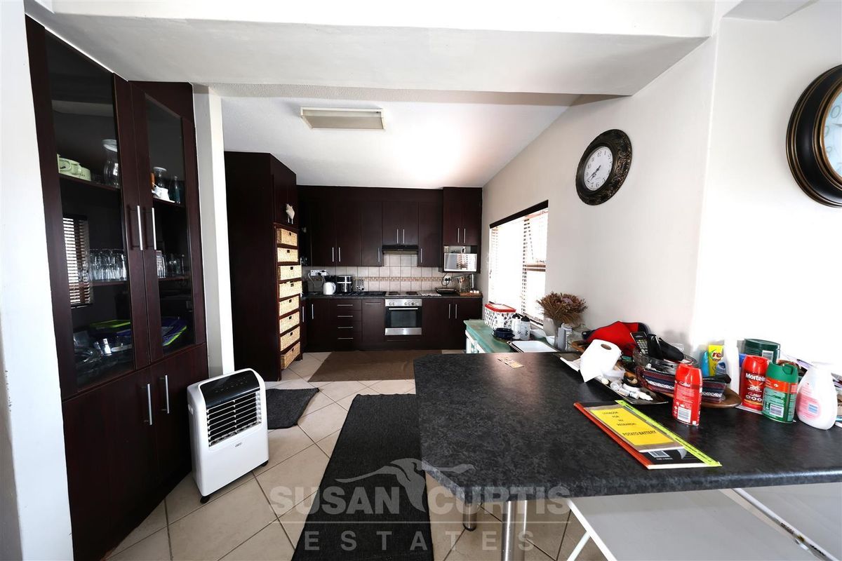 A functional kitchen featuring dark wood cabinetry, built-in oven, hob, extractor fan, and a breakfast counter with tiled flooring.