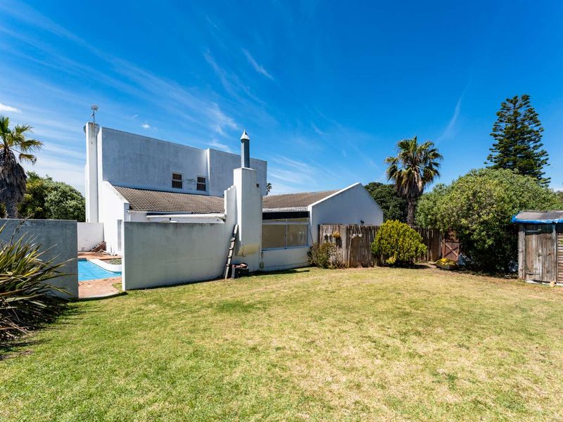 Rear view of the property featuring a private garden, swimming pool, and external chimney stack set against a clear blue sky.