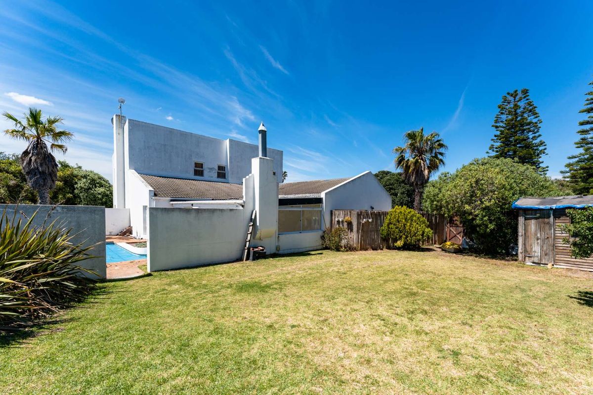 Rear view of the property featuring a private garden, swimming pool, and external chimney stack set against a clear blue sky.