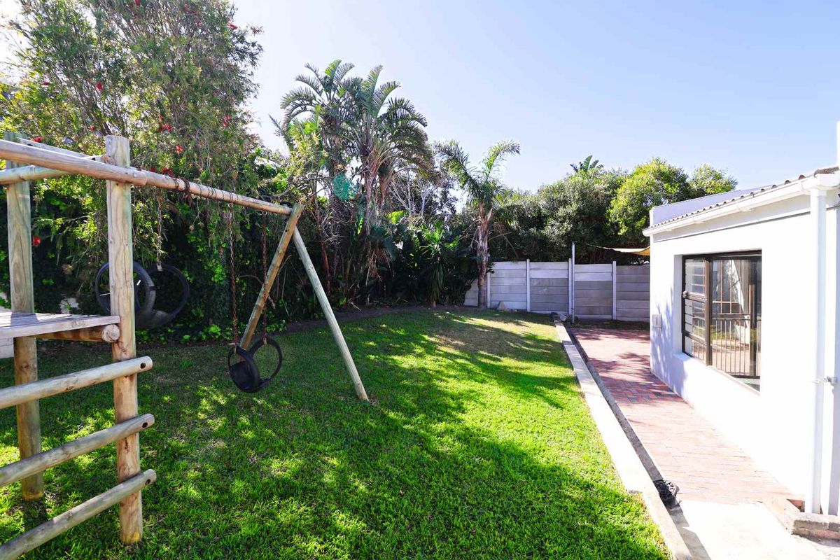 A private rear garden featuring a lawn, brick paved pathway, and precast concrete boundary wall, providing a functional outdoor space.