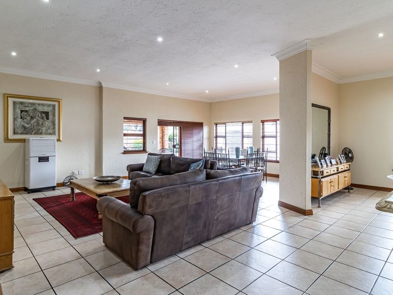 Spacious open-plan living and dining area featuring neutral walls, ceramic tiled flooring, recessed lighting, and large windows providing ample natural light.