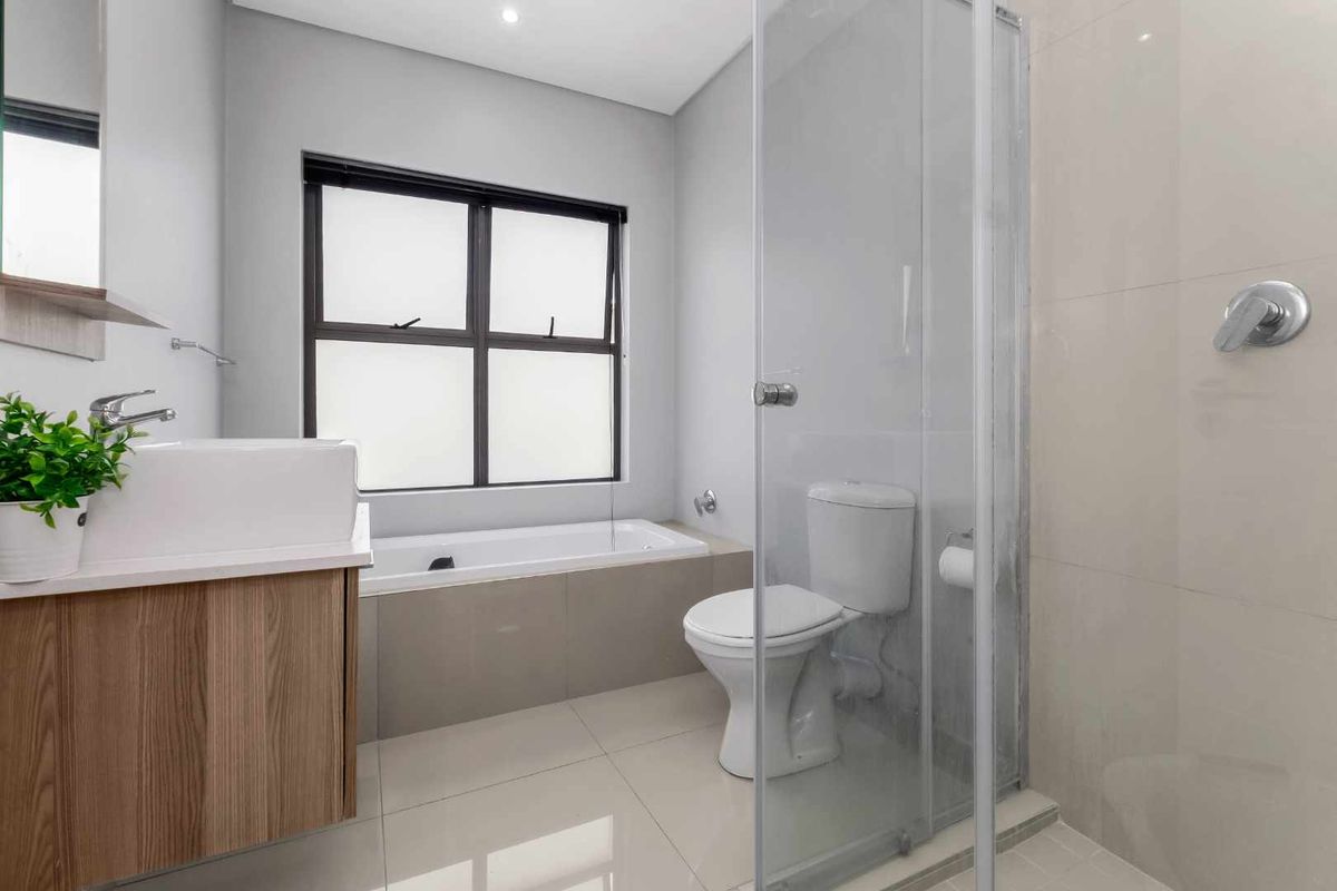 Modern bathroom featuring a vessel sink vanity, built-in bathtub, and a separate glass-enclosed shower with neutral tiling throughout.
