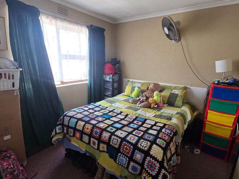 A standard bedroom featuring a wall-mounted fan and a window with curtains, providing a functional living space.