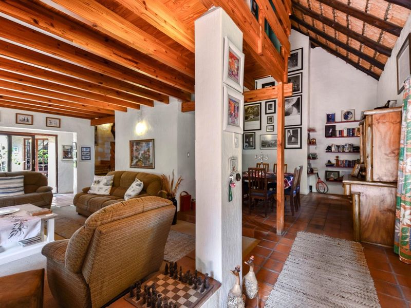 Spacious open-plan living and dining area featuring exposed timber beams, a high thatched ceiling, and traditional terracotta floor tiles.
