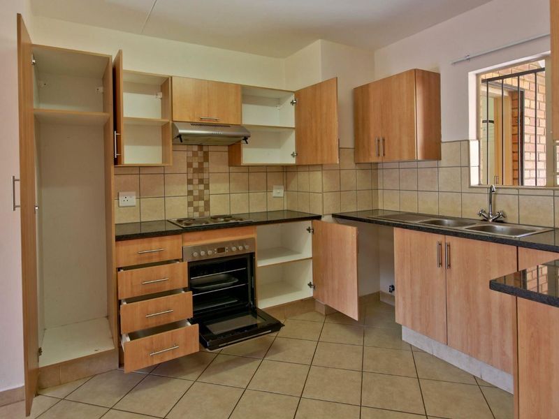 A functional kitchen featuring laminate cabinetry, granite countertops, a built-in oven with hob, and tiled flooring, offering a practical layout for daily use.