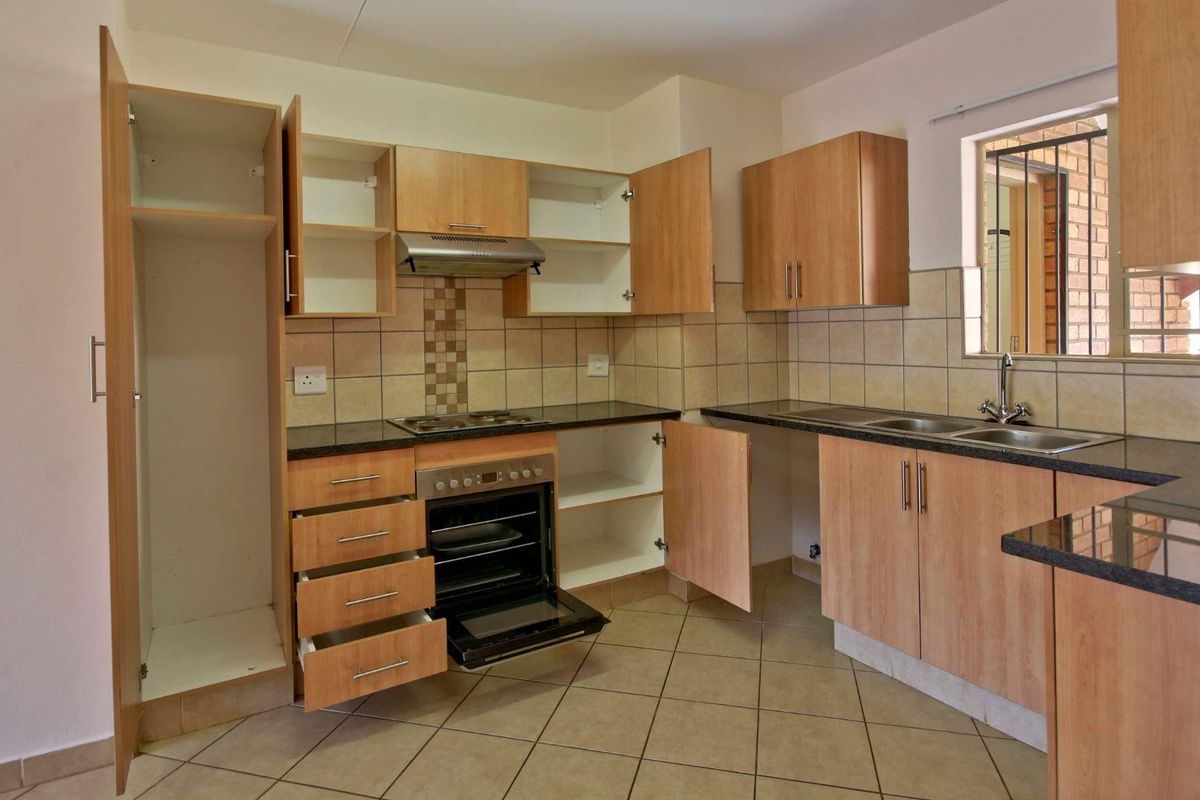 A functional kitchen featuring laminate cabinetry, granite countertops, a built-in oven with hob, and tiled flooring, offering a practical layout for daily use.