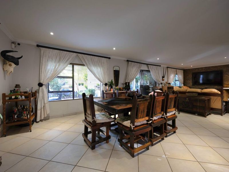 Spacious open-plan living and dining area featuring tiled flooring, recessed lighting, and a stone feature wall with direct access to the outdoor space.