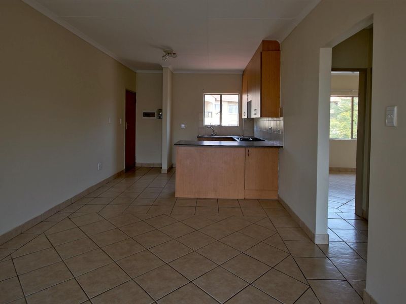 An open-plan living and kitchen area featuring tiled flooring and functional built-in cabinetry with a hob and extractor fan.