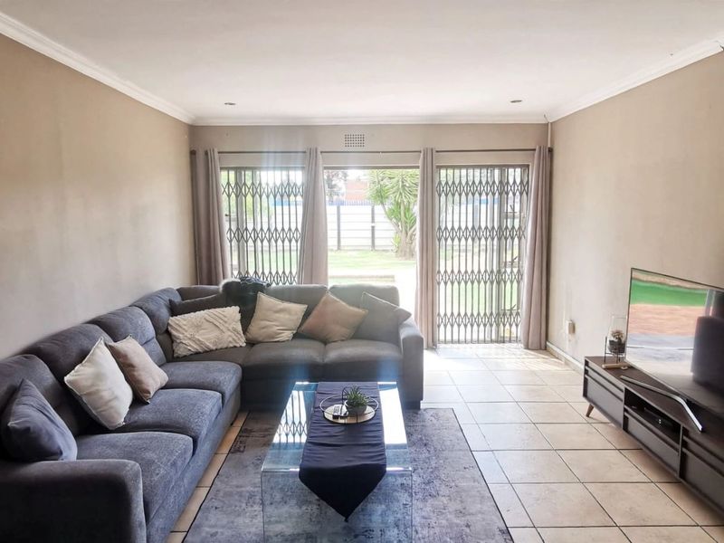 Spacious living room featuring tiled flooring, recessed lighting, and large sliding glass doors with security gates providing access to the rear garden.