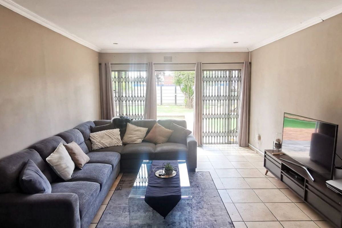 Spacious living room featuring tiled flooring, recessed lighting, and large sliding glass doors with security gates providing access to the rear garden.