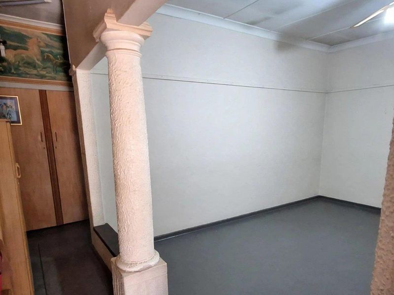 An empty living area featuring a decorative column, built-in storage cabinetry, and a ceiling fan, offering a blank canvas for interior design updates.