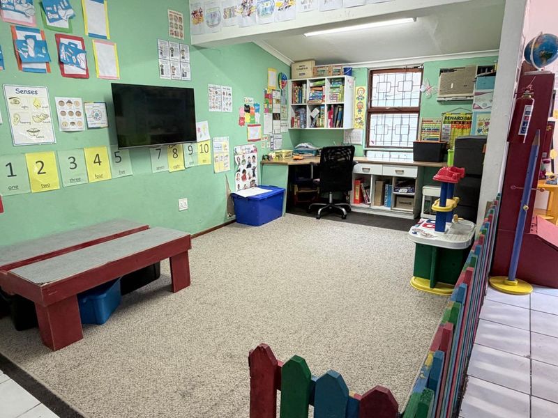 A multi-purpose room currently utilized as a learning space, featuring built-in desk cabinetry, shelving, and a wall-mounted air conditioning unit.