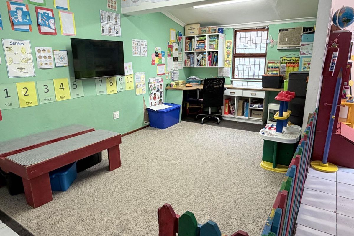 A multi-purpose room currently utilized as a learning space, featuring built-in desk cabinetry, shelving, and a wall-mounted air conditioning unit.