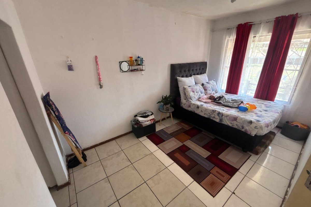 A bedroom featuring tiled flooring and a window with security bars, offering a functional space ready for cosmetic updates.