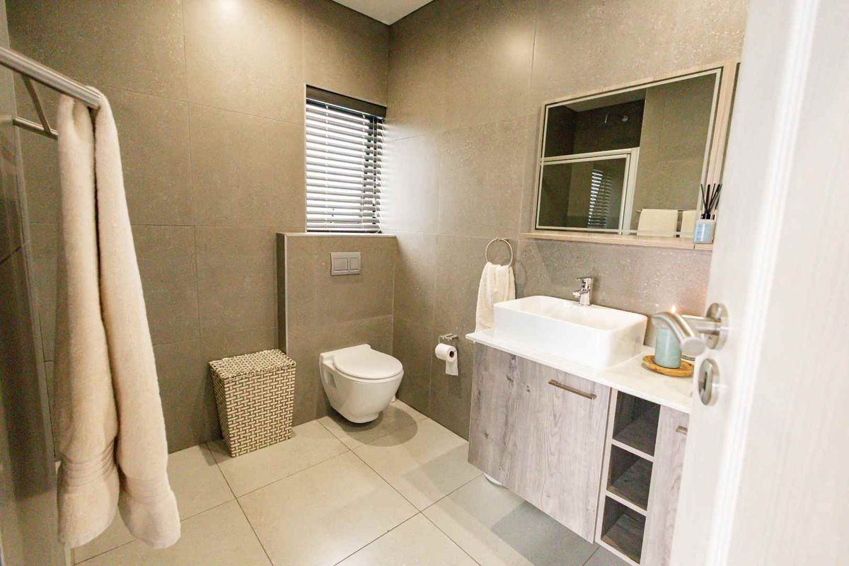Modern bathroom featuring large format wall tiles, a wall-mounted toilet, and a contemporary vanity with a vessel sink.