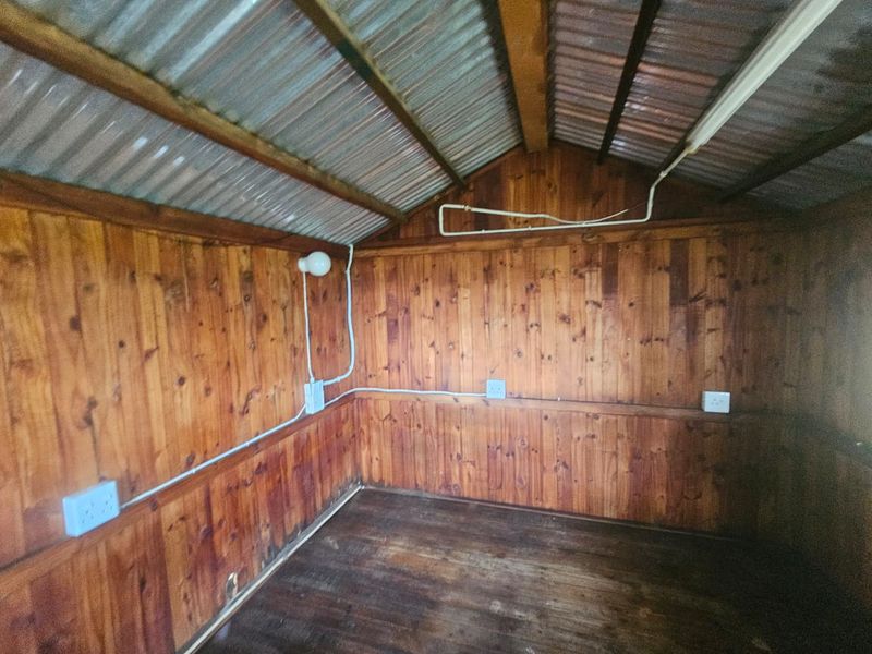 A rustic utility space featuring timber wall cladding, exposed corrugated metal roofing, and surface-mounted electrical infrastructure.