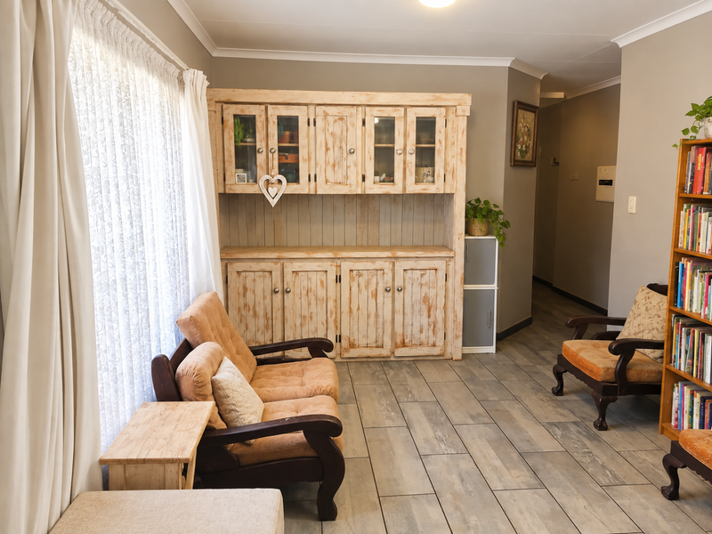 A living room featuring wood-look tiled flooring, coved ceilings, and a large built-in wooden display cabinet providing ample storage space.