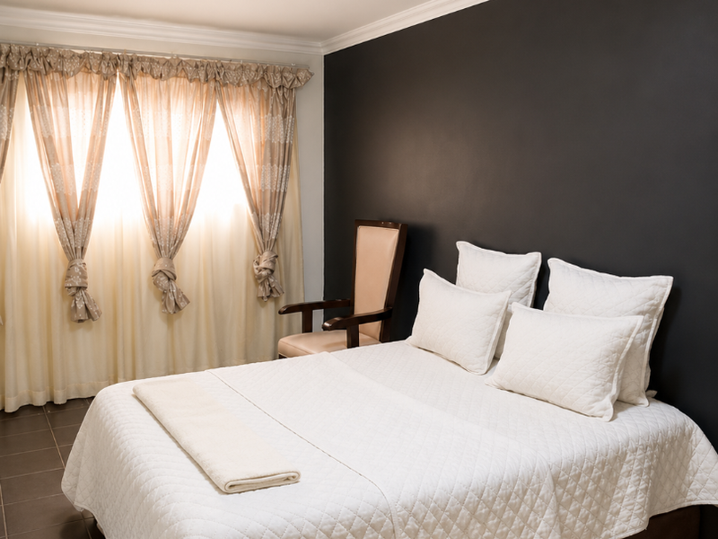 A well-maintained bedroom featuring dark accent wall, tiled flooring, and crown molding, providing a clean and neutral foundation for personal styling.