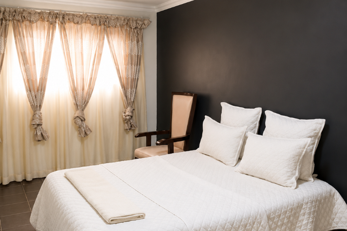 A well-maintained bedroom featuring dark accent wall, tiled flooring, and crown molding, providing a clean and neutral foundation for personal styling.