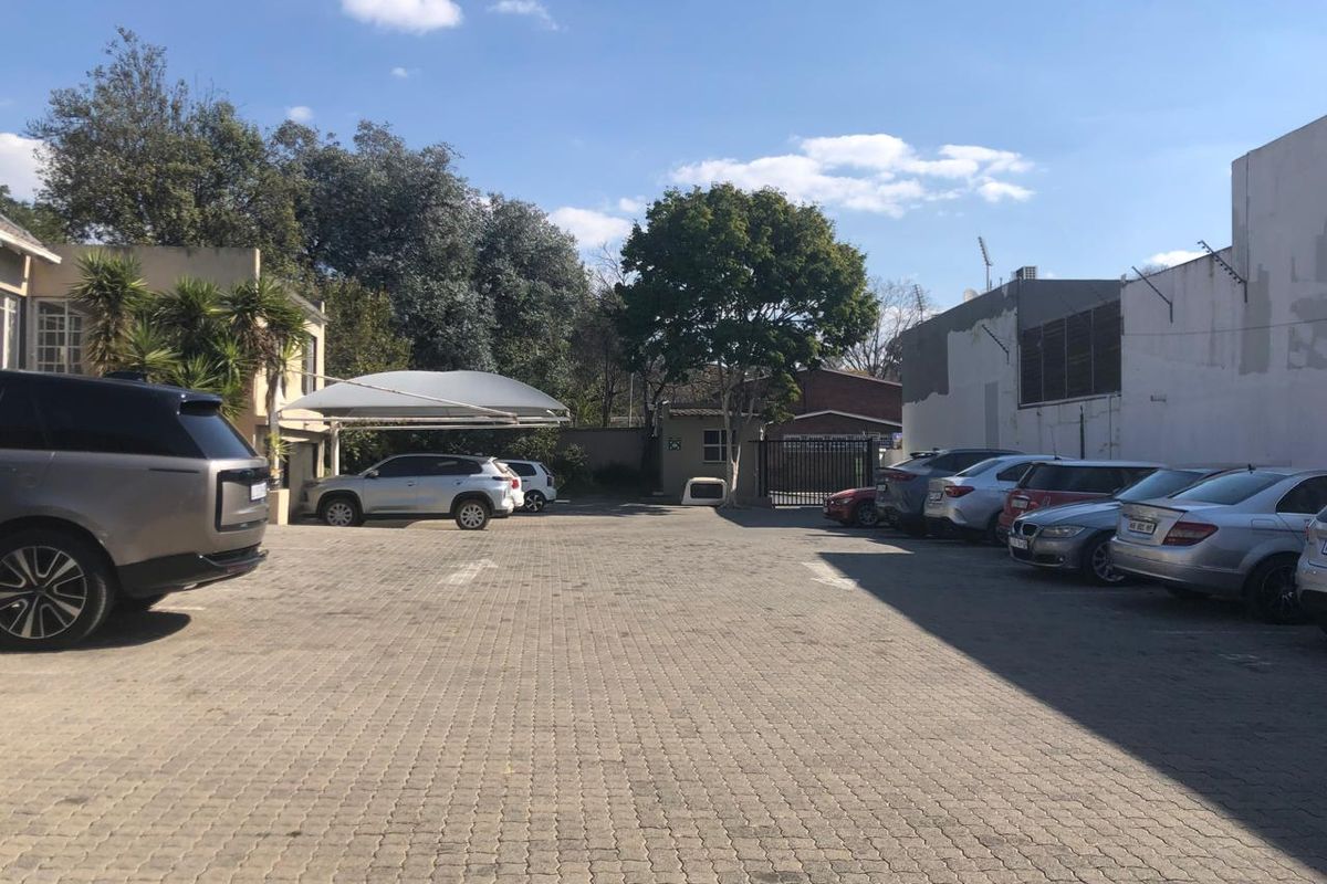 Exterior view of the office property featuring a paved parking area, shade port, and secure gated access.