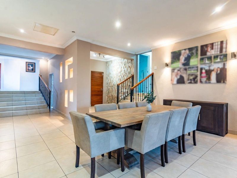 Spacious dining area featuring tiled flooring, a stone feature wall, recessed wall niches, and an open-plan staircase with metal railings.