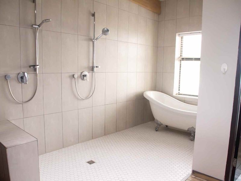 Modern bathroom featuring a spacious walk-in shower with dual shower heads and a classic freestanding clawfoot bathtub.