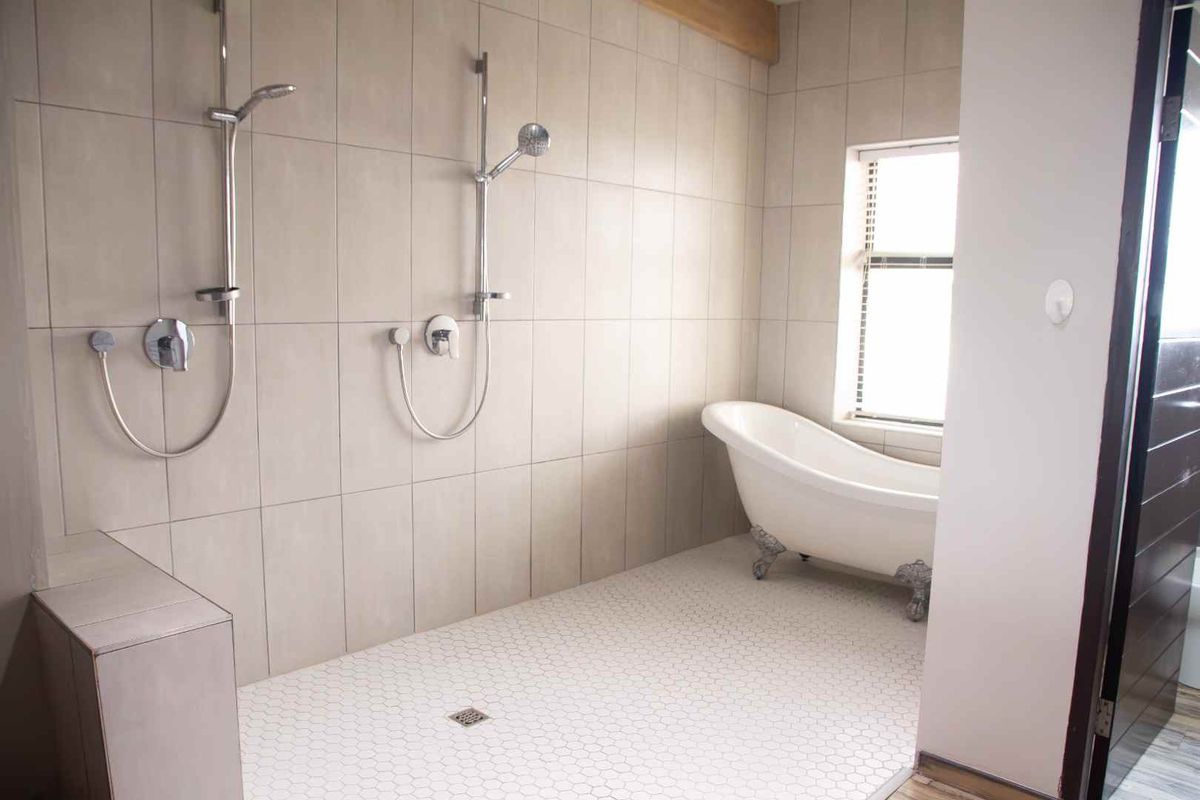 Modern bathroom featuring a spacious walk-in shower with dual shower heads and a classic freestanding clawfoot bathtub.