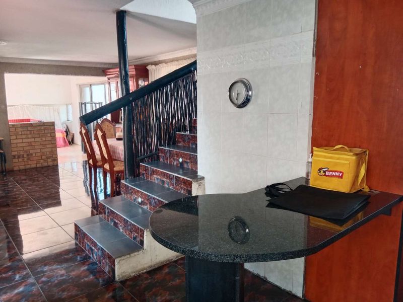 Open plan living area featuring a tiled staircase with a granite breakfast bar and tiled wall finishes.
