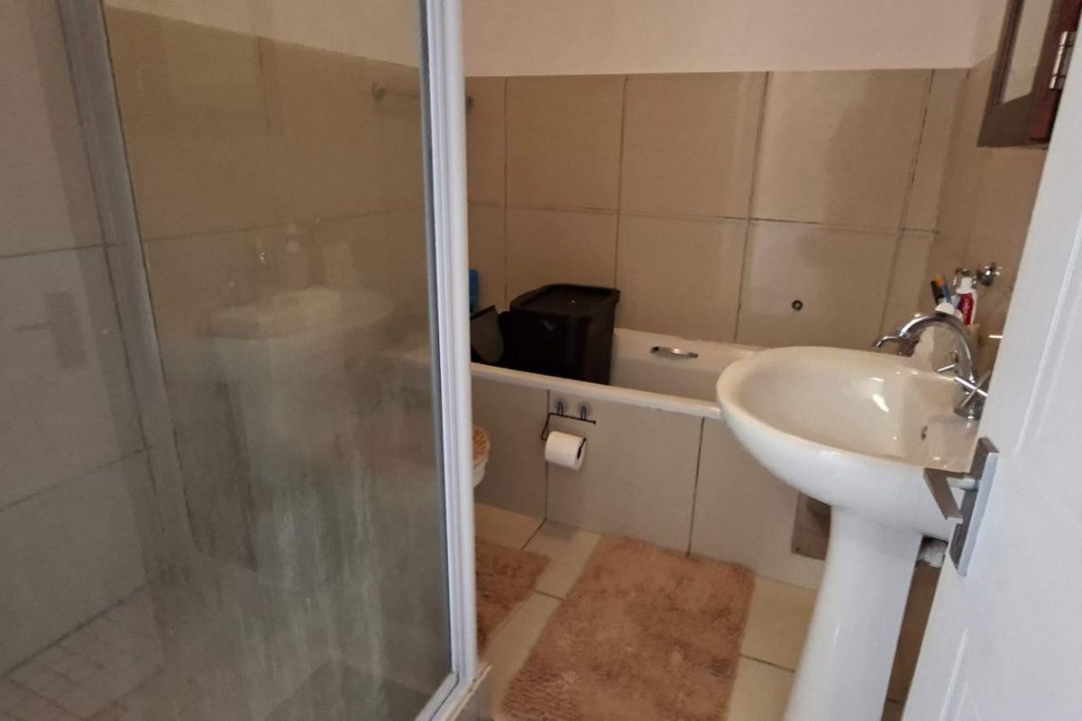 A functional bathroom featuring a pedestal basin, a separate shower enclosure, and a bathtub with tiled wall finishes.